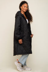 woman wearing a black quilted hooded coat over a white top and light jeans, with curly hair and sneakers