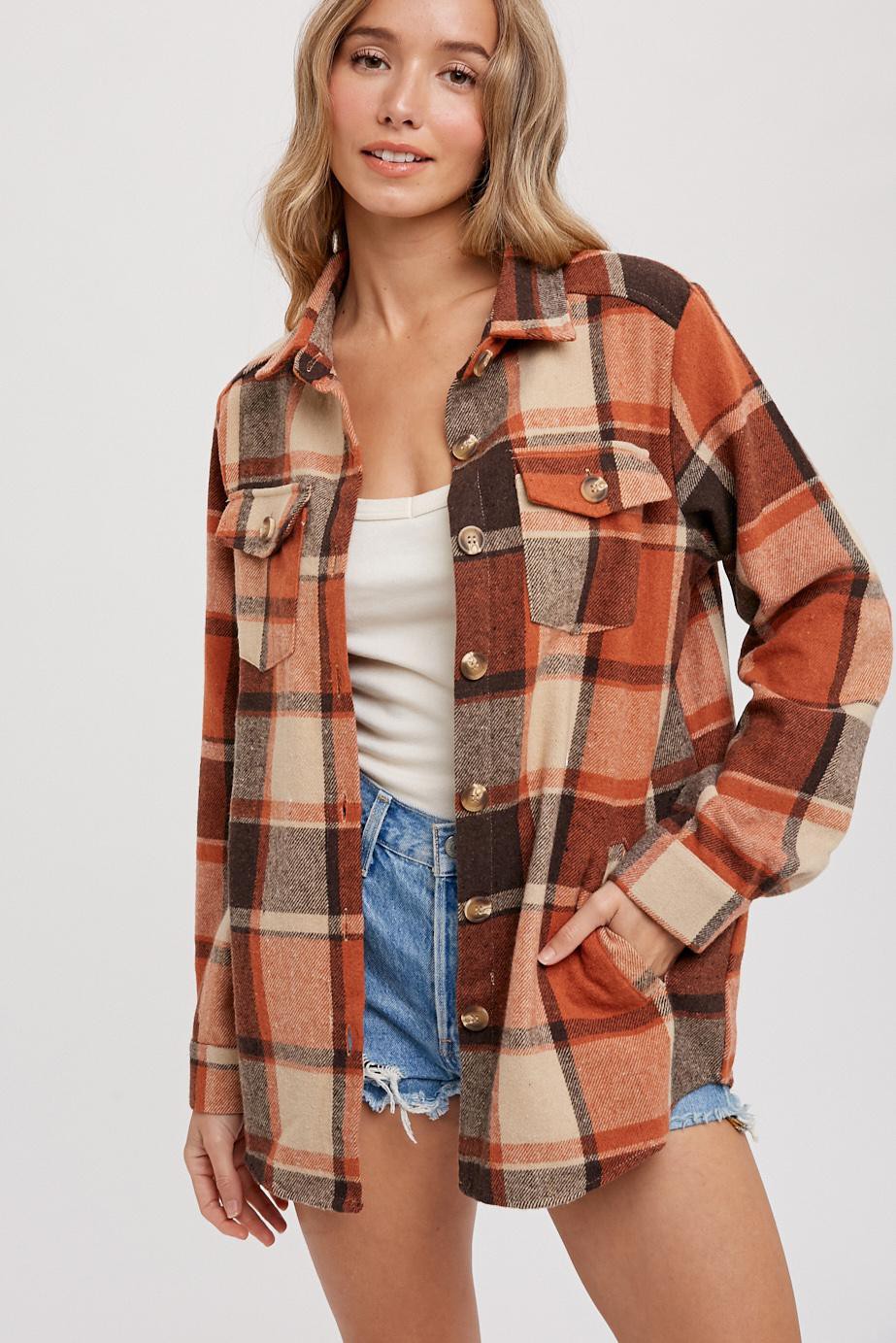 woman wearing an orange and cream plaid flannel shirt, styled with a white tank top and denim shorts