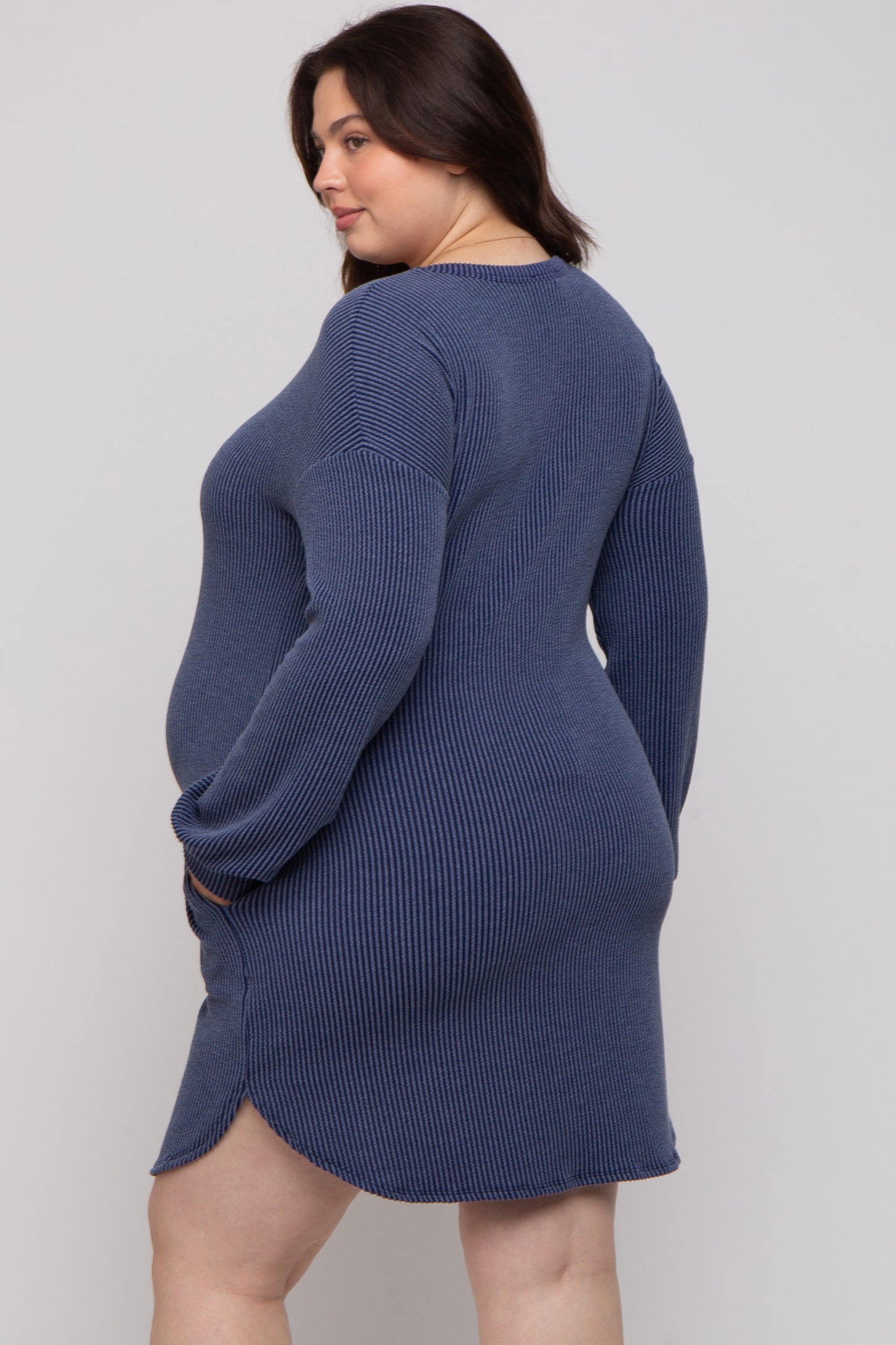 woman wearing a navy blue ribbed maternity dress with long sleeves and a side slit, showing her baby bump