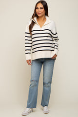 woman wearing a striped cream and black maternity pullover sweater with a quarter zip and distressed light blue jeans