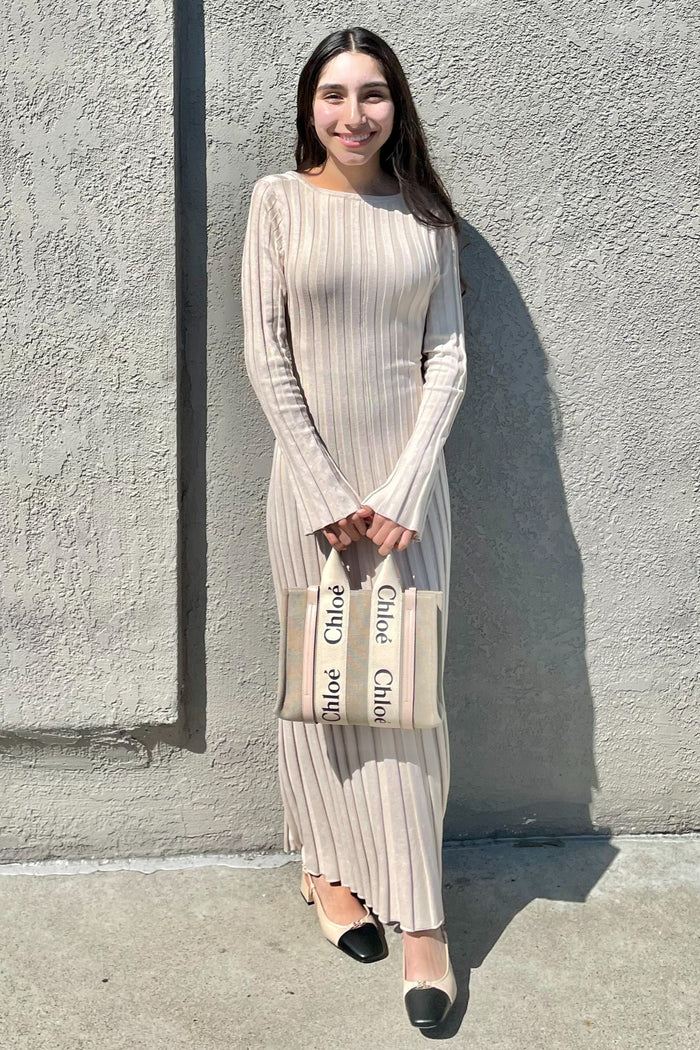 woman wearing a beige ribbed long sleeve maxi dress with a black and cream handbag and espadrille flats