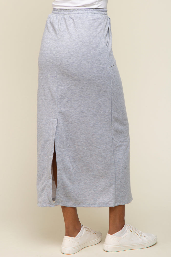 woman wearing a light gray maxi skirt with side slits and a casual fit, paired with white sneakers