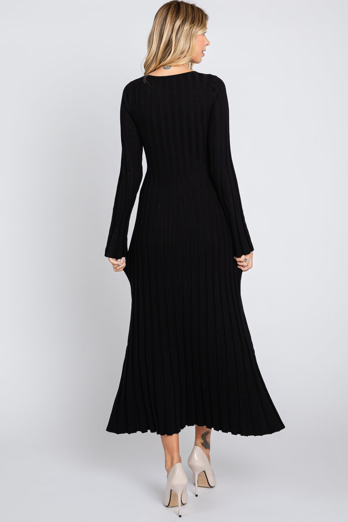 woman wearing a black ribbed midi dress with long sleeves, seen from the back, paired with light-colored heels