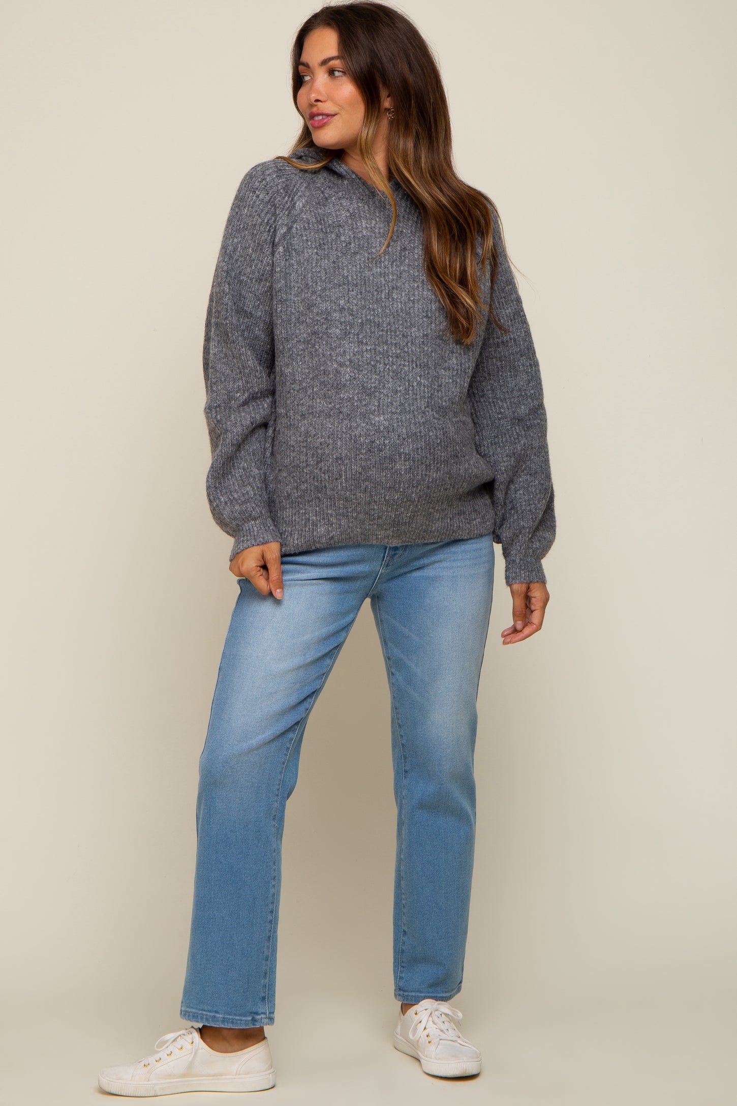 woman wearing a gray maternity sweater with puff sleeves and light blue maternity jeans