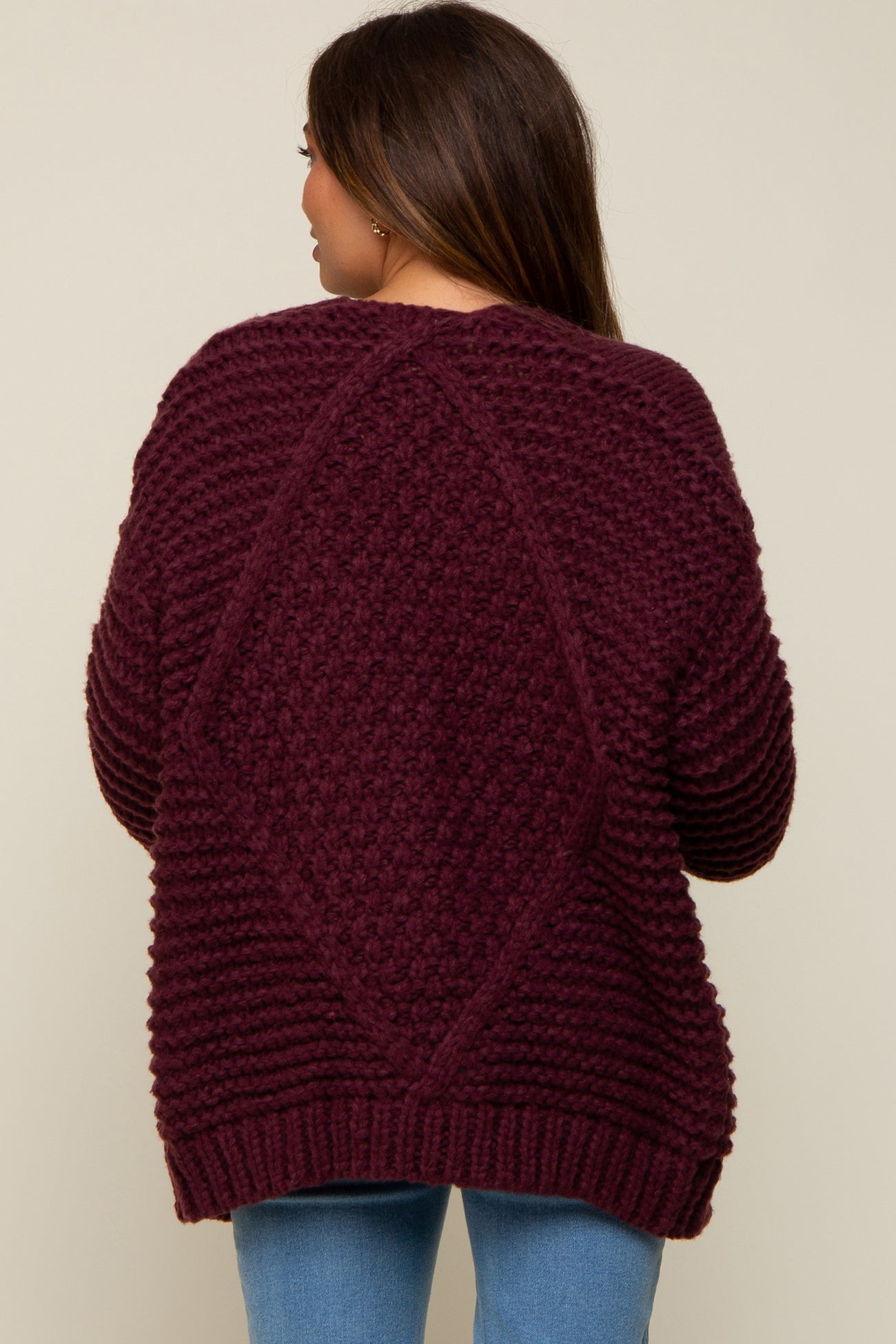 woman wearing a burgundy maternity sweater with a textured design and relaxed fit, featuring a diamond pattern on the back