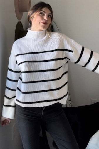 woman wearing a white and black striped turtleneck sweater with long sleeves and a relaxed fit