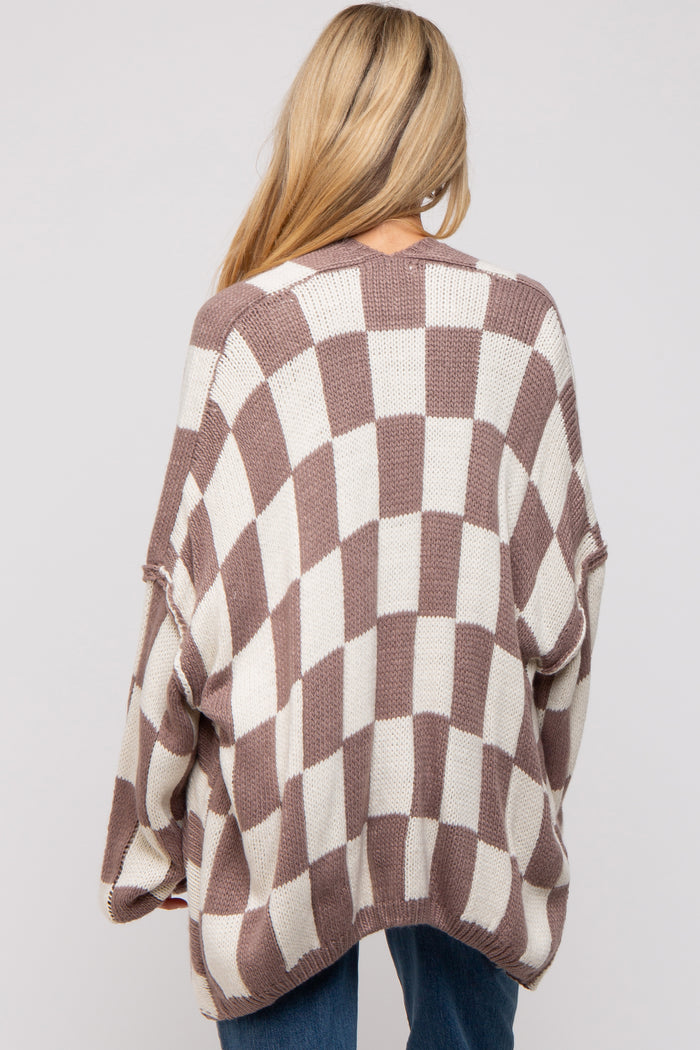 woman wearing a brown and cream checkered oversized maternity sweater, showing the back view