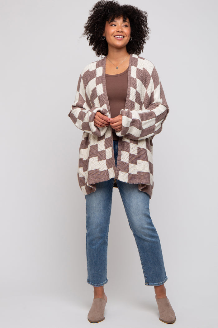 woman wearing a brown and cream checkered cardigan over a brown tank top, paired with light blue jeans and beige mules