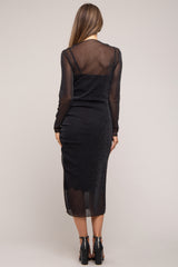 woman wearing a black sheer long sleeve maternity dress with a fitted silhouette and a mid-calf length