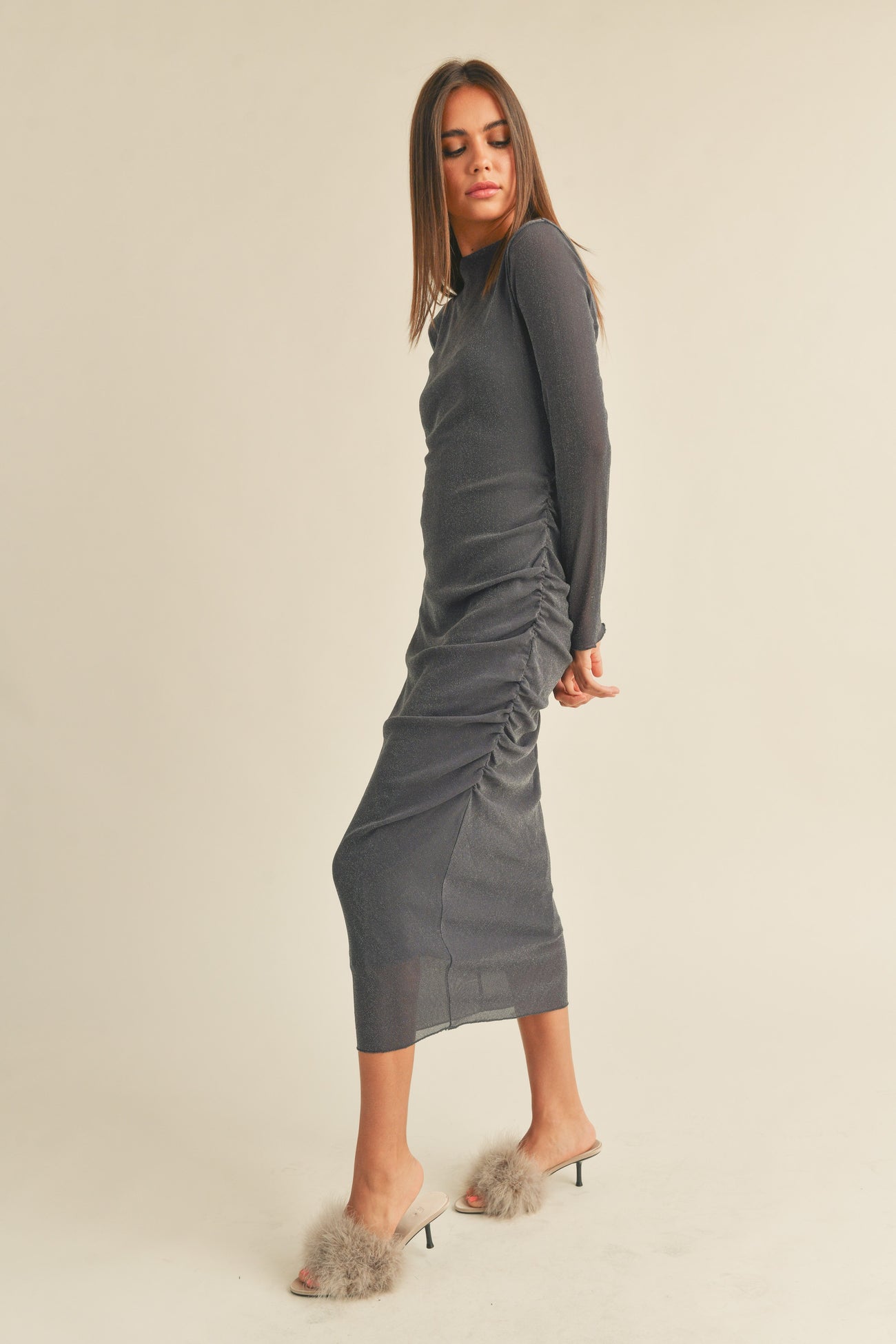 woman wearing a charcoal gray long sleeve ruched midi dress and stylish fuzzy slip-on heels