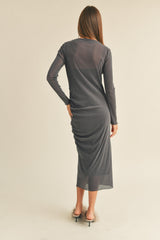 woman wearing a fitted charcoal gray long sleeve midi dress with ruching details at the back