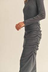 woman wearing a dark gray long sleeve fitted dress with ruching detail along the side