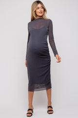 woman wearing a dark gray long sleeve maternity dress with ruched detailing and a form-fitting silhouette, showcasing a baby bump
