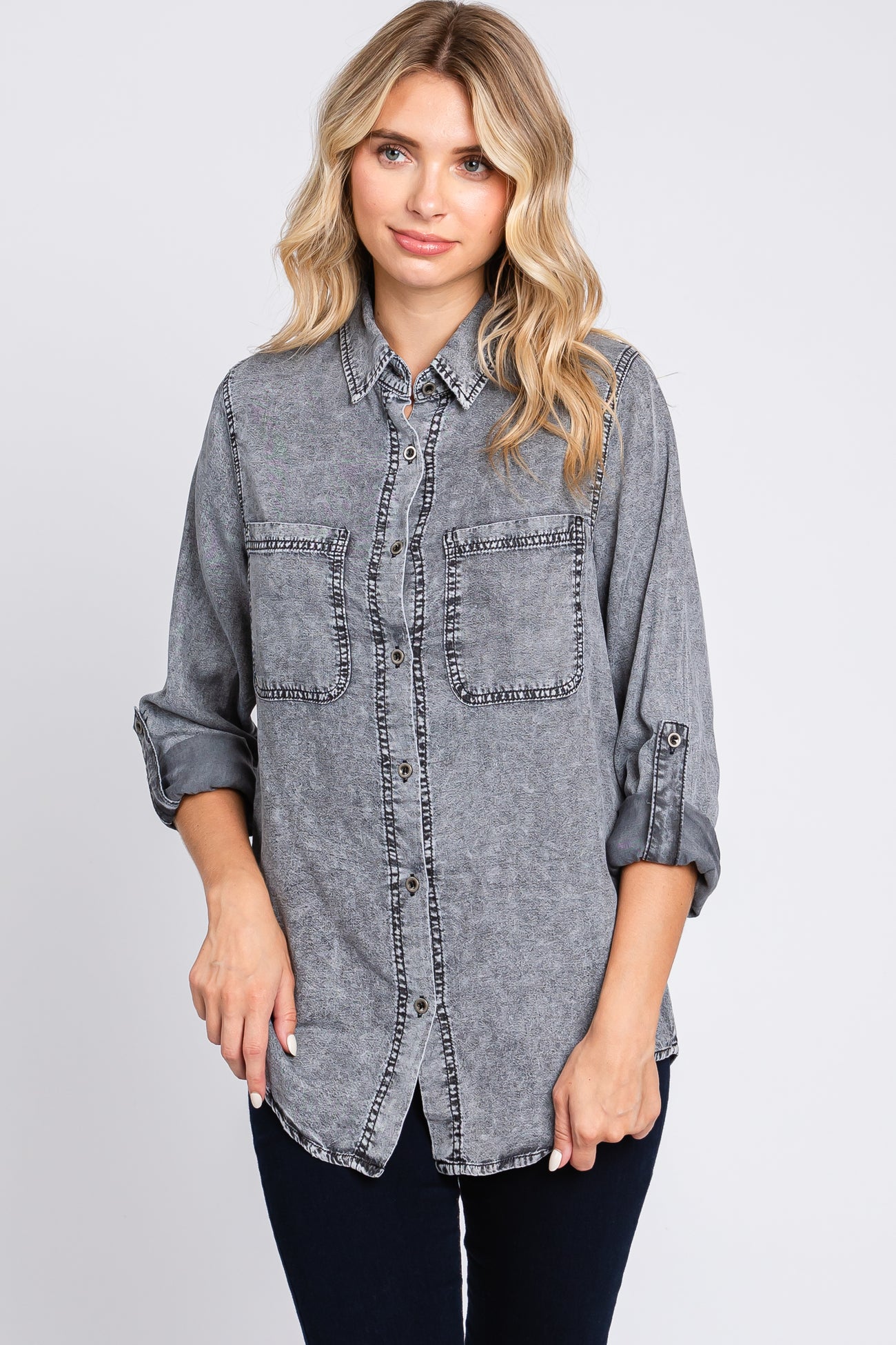 woman wearing a gray denim shirt with two chest pockets and contrast stitching, styled with rolled sleeves