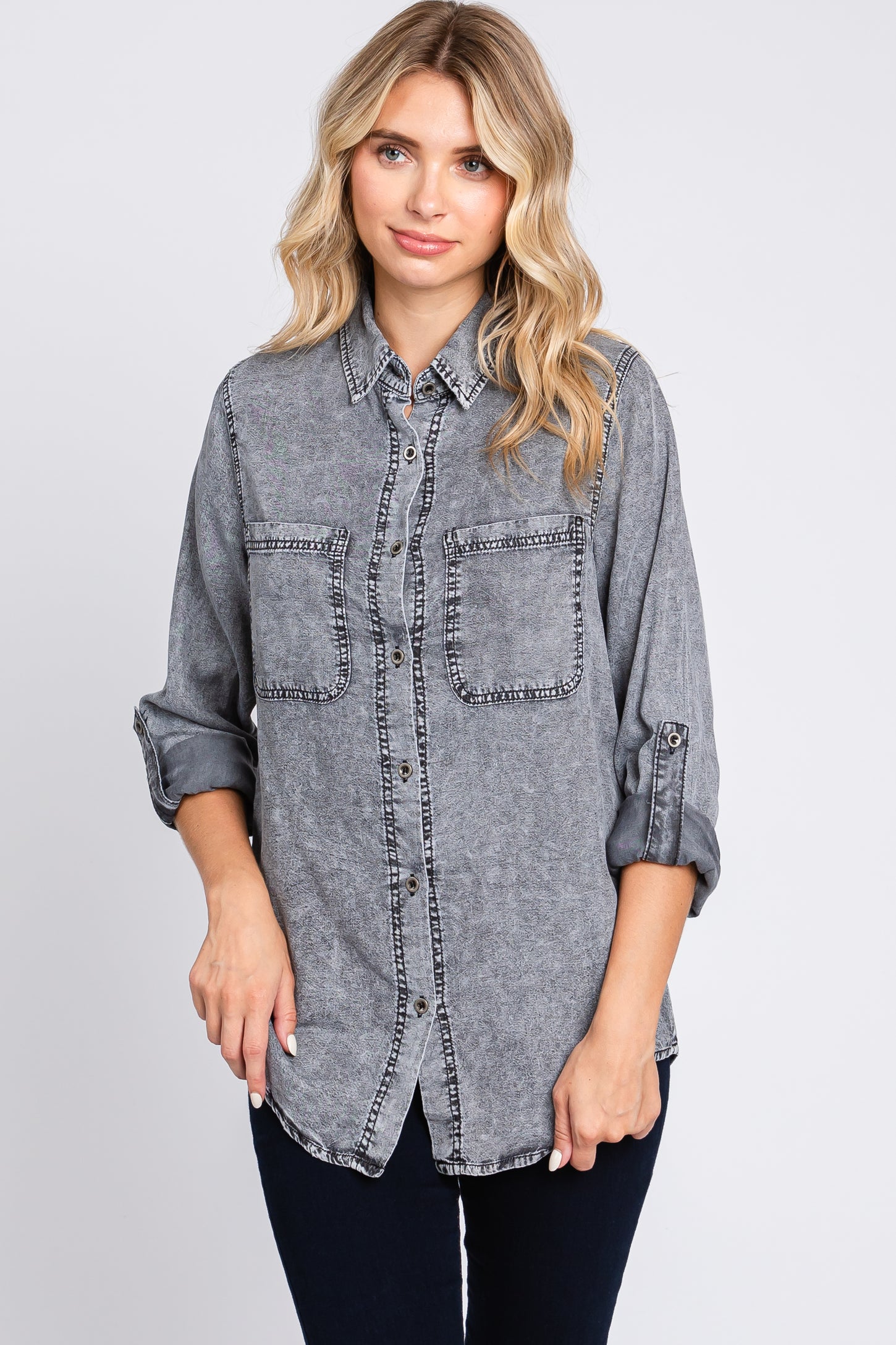 woman wearing a gray denim shirt with two chest pockets and contrast stitching, styled with rolled sleeves