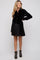 woman wearing a black velvet maternity shirt dress with button details and long sleeves, featuring a fitted waist and flared skirt