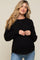 woman wearing a black maternity sweater with a textured knit pattern and a visible baby bump, paired with light blue jeans