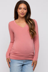 woman wearing a pink long sleeve maternity top with a v-neck and visible baby bump