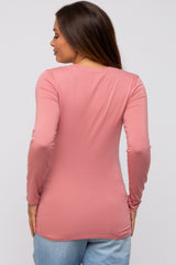 woman wearing a light pink long sleeve maternity top viewed from the back