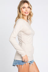 woman wearing a beige long sleeve top with a slim fit, paired with denim shorts