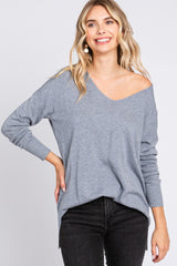 woman wearing a light gray off-the-shoulder sweater with long sleeves and a relaxed fit, paired with black jeans