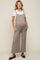 woman wearing a light brown maternity jumpsuit with pockets over a white t-shirt and showing a baby bump