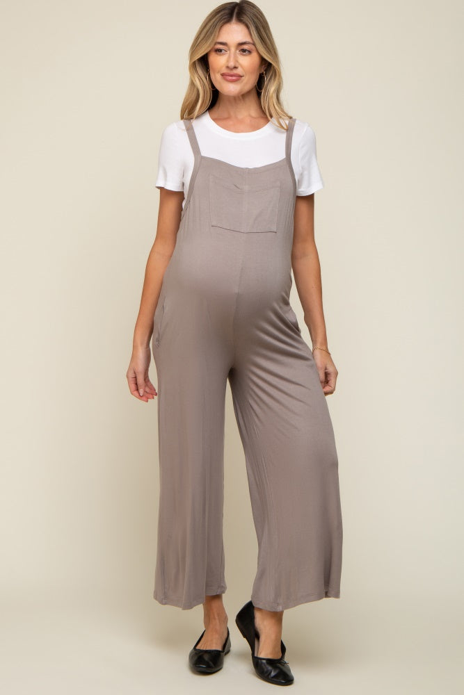 woman wearing a taupe maternity jumpsuit over a white t-shirt, showing her baby bump