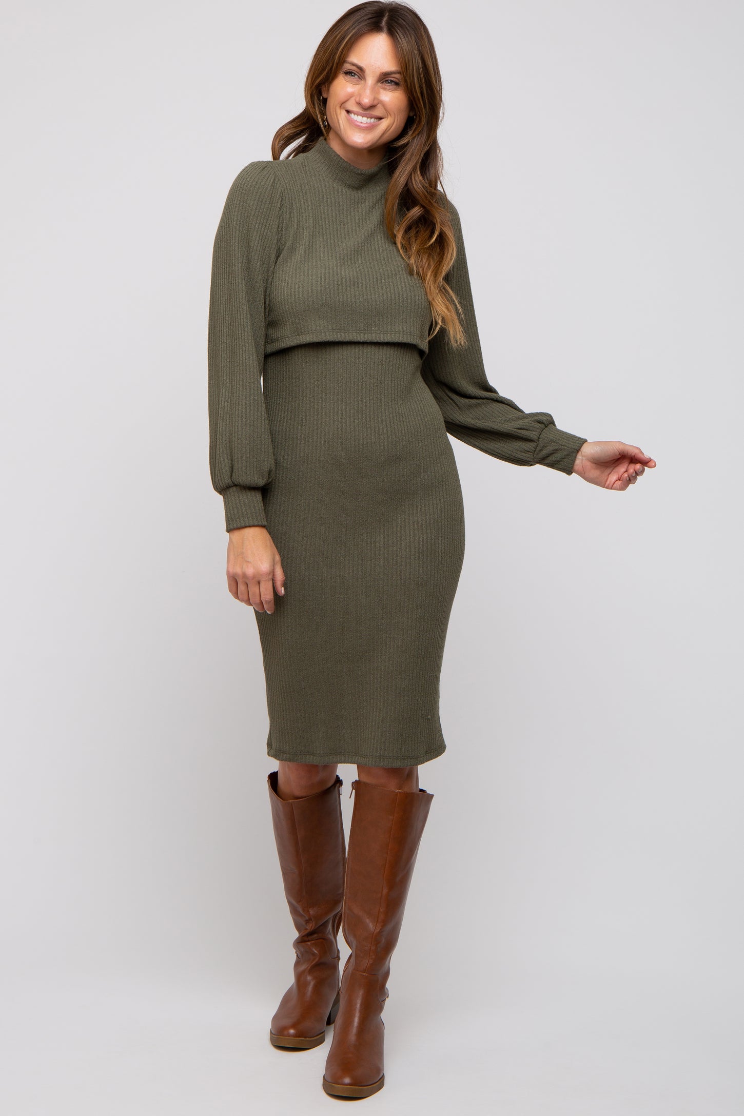 woman wearing an olive green ribbed sweater dress with long sleeves and a mock neck, paired with brown knee-high boots