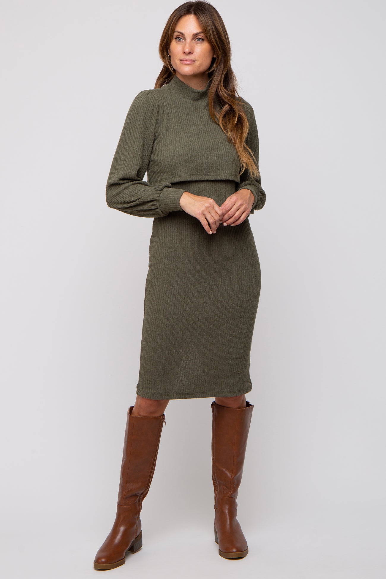 woman wearing an olive green ribbed midi dress with a high neckline and long sleeves, paired with brown knee-high boots