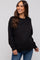 woman wearing a black maternity sweatshirt and smiling, showcasing her baby bump with blue jeans