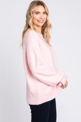 woman wearing a soft pink oversized sweater with ribbed hem and long sleeves, smiling at the camera