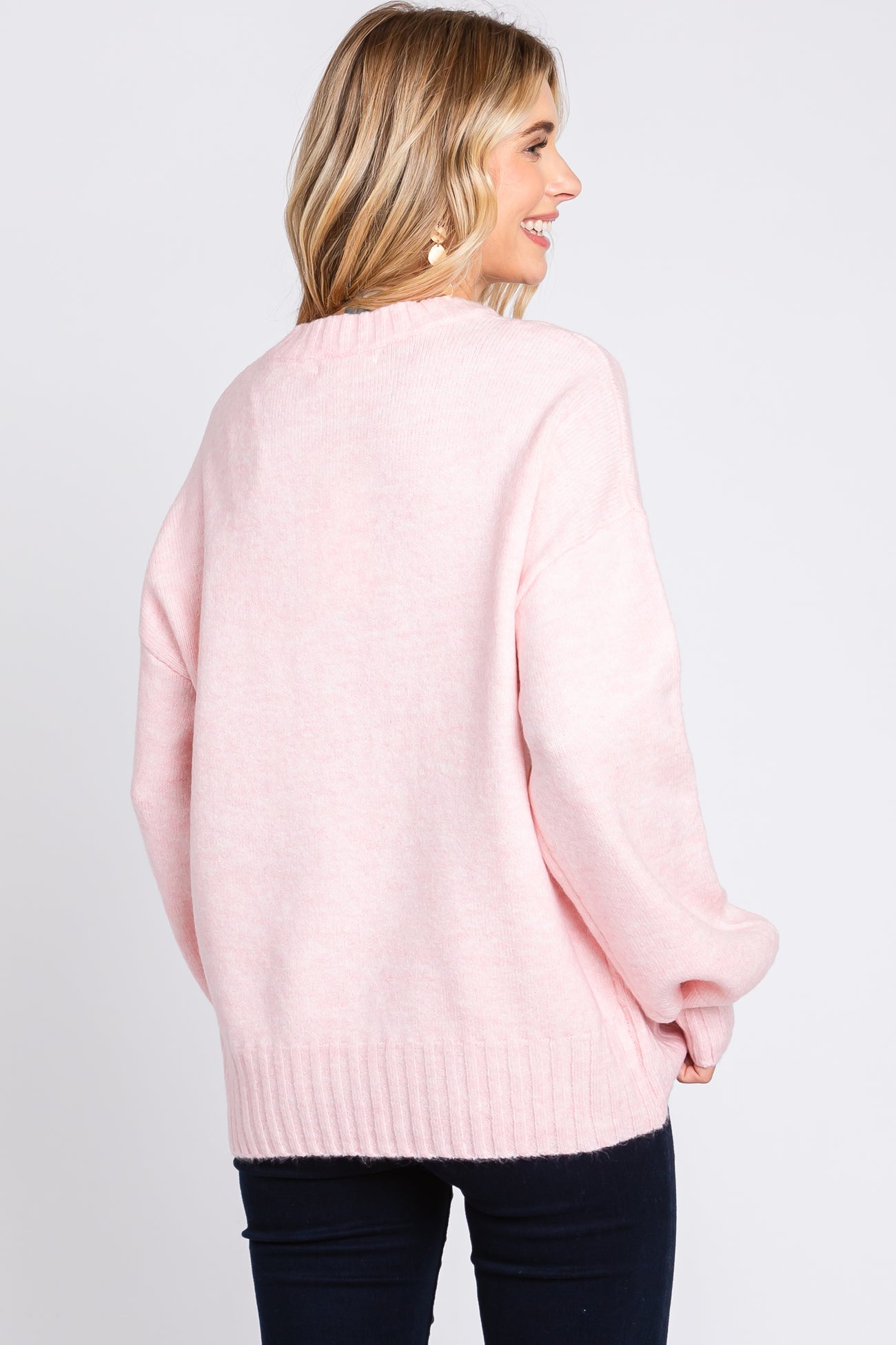 woman wearing a soft pink oversized sweater with a ribbed hem, styled for a relaxed fit