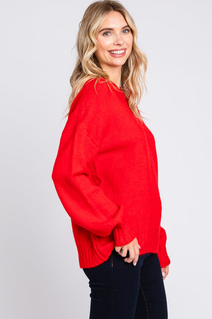 woman wearing a bright red oversized sweater with balloon sleeves and a ribbed hem, paired with dark jeans