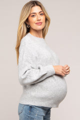 woman wearing a grey maternity sweater with a relaxed fit and a visible baby bump