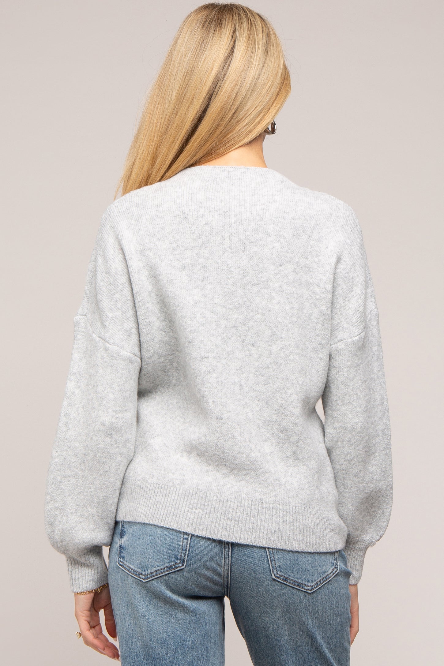woman wearing a gray oversized maternity sweater with dropped shoulders and a relaxed fit, seen from the back