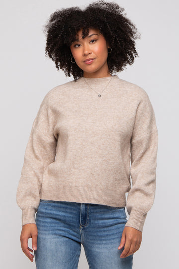 woman wearing a beige oversized sweater with balloon sleeves and paired with blue jeans