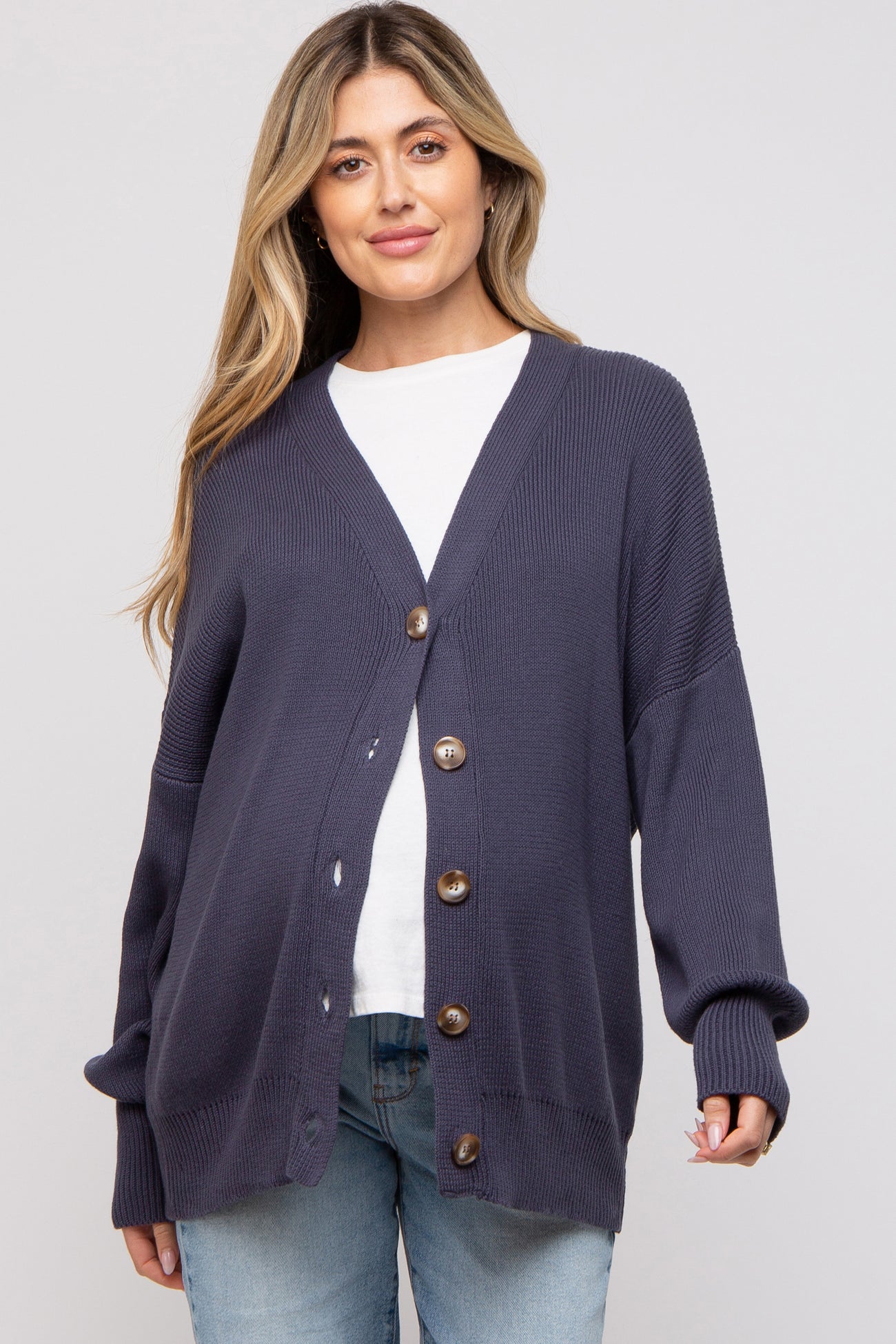 woman wearing a navy blue maternity cardigan with buttons and a v-neck, styled over a white t-shirt and jeans
