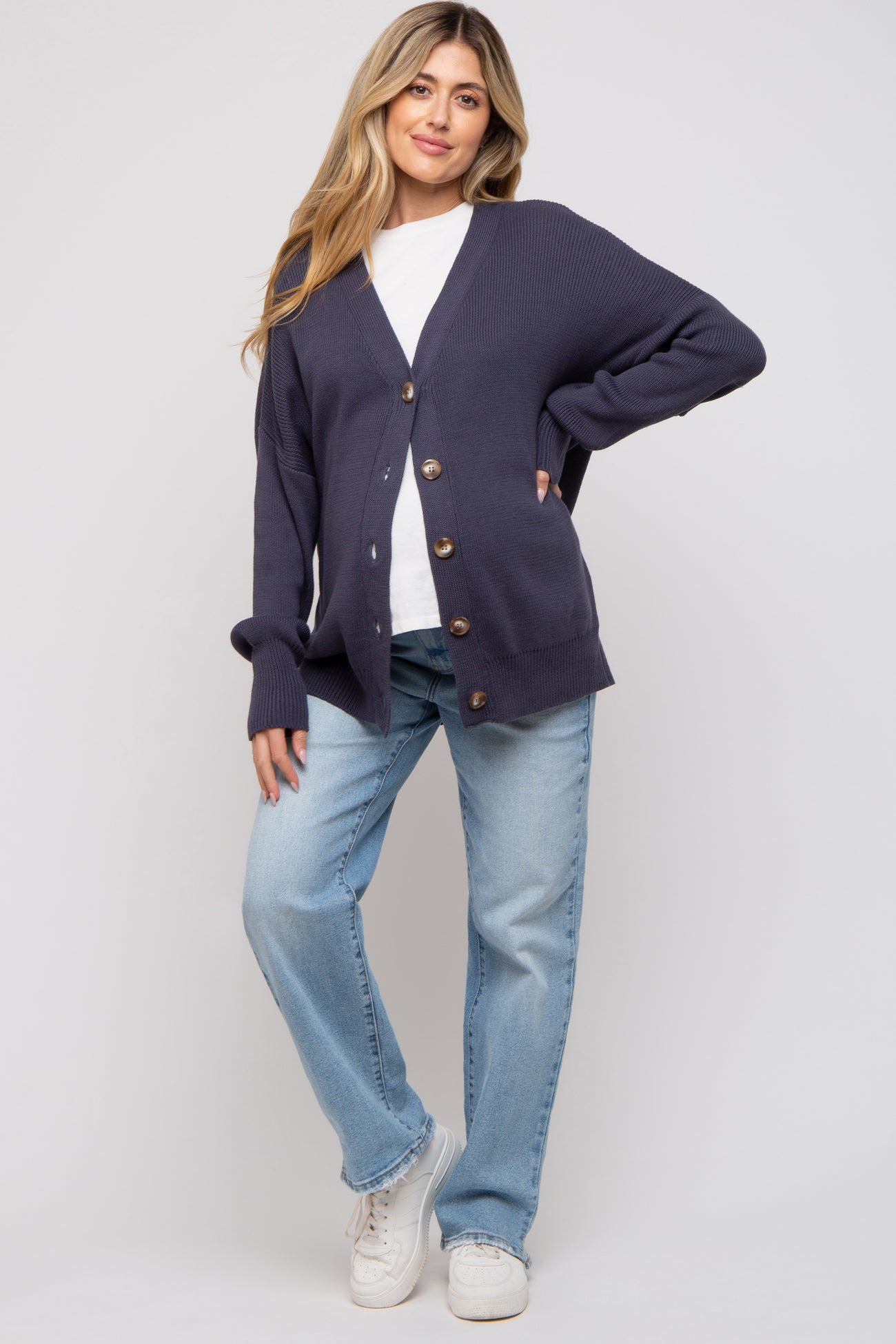 woman wearing a navy blue ribbed maternity cardigan with buttons, paired with a white t-shirt and light blue jeans
