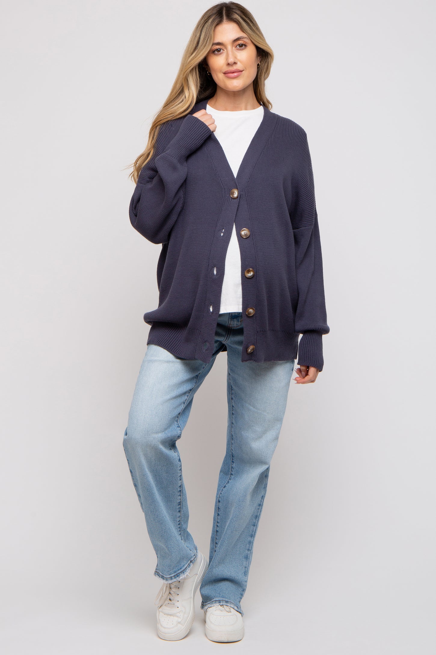 woman wearing a navy blue maternity cardigan with buttons over a white top and light blue jeans