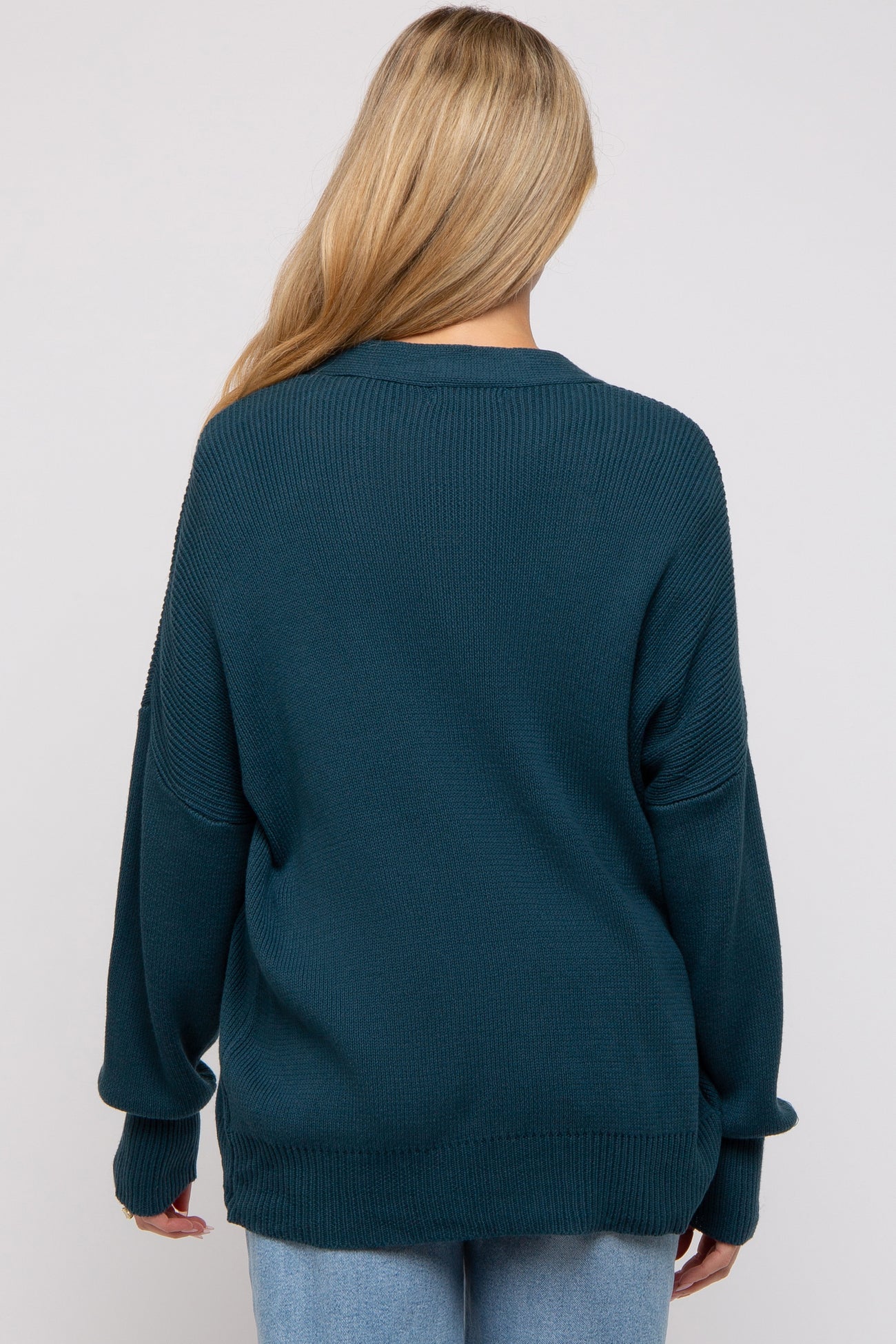 woman wearing a dark teal oversized maternity sweater with a relaxed fit and dropped shoulders
