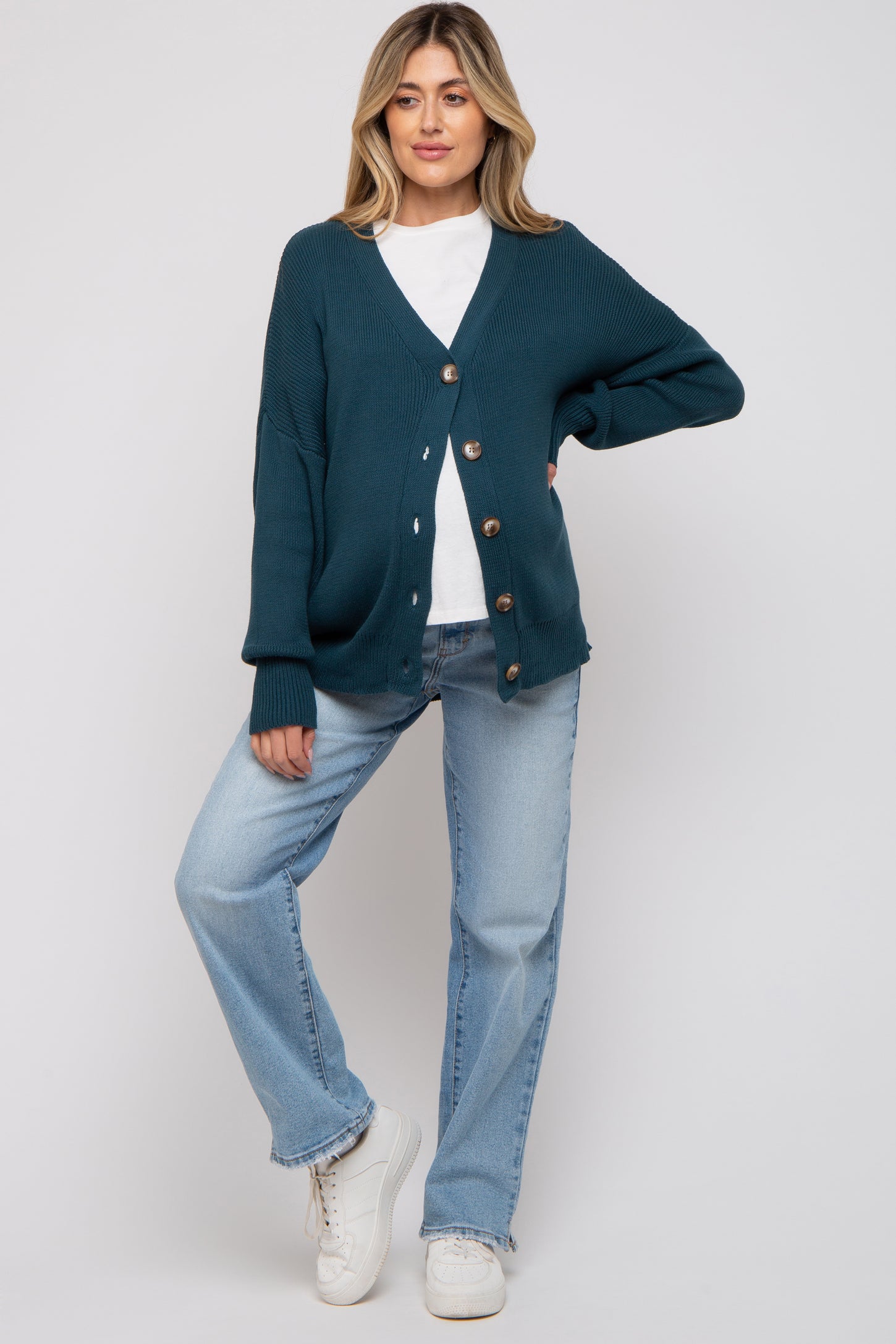 woman wearing a teal maternity cardigan with buttons, styled with a white t-shirt and light blue jeans