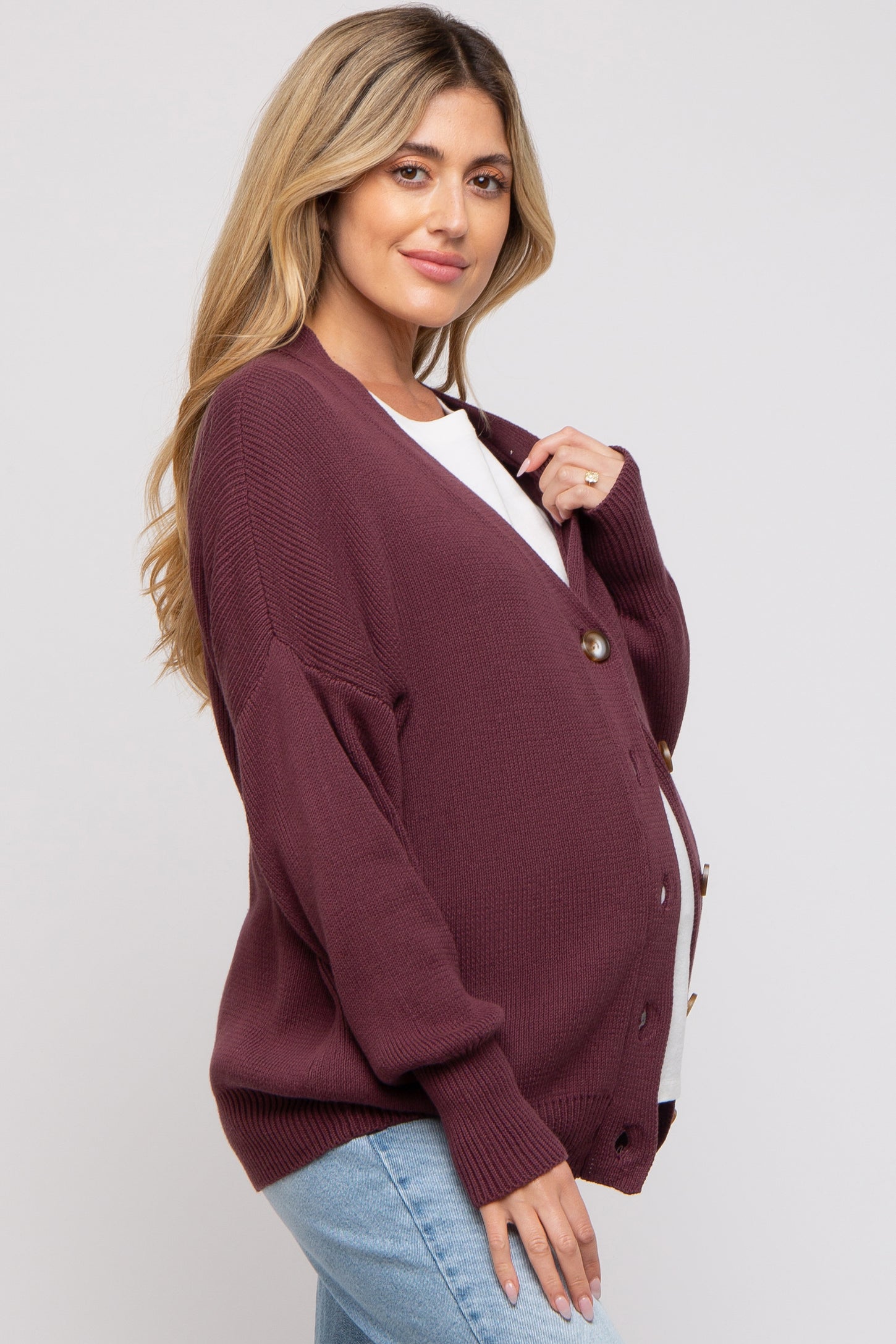 woman wearing a burgundy maternity cardigan over a white top, showcasing her baby bump with a relaxed fit and button details