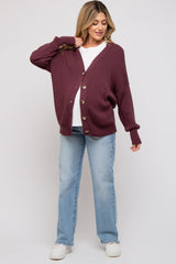 woman wearing a burgundy maternity cardigan with buttons, paired with a white top and light blue jeans, featuring a baby bump