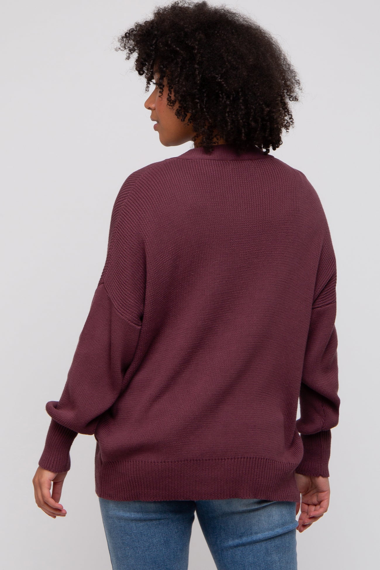 woman wearing a maroon oversized sweater with a relaxed fit and dropped shoulders, seen from the back