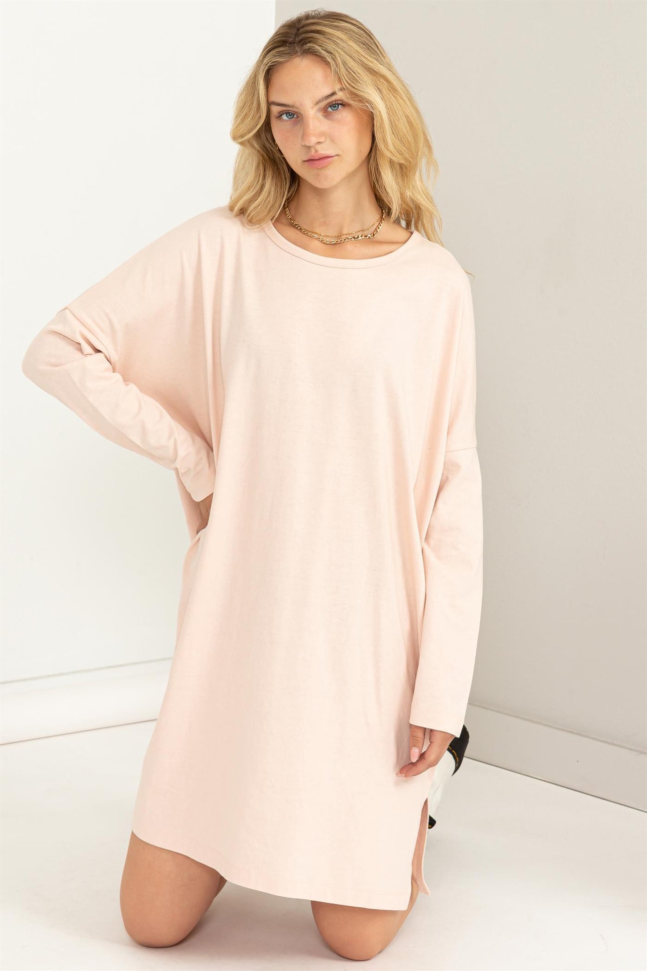 woman wearing a light pink oversized long sleeve dress with side slits