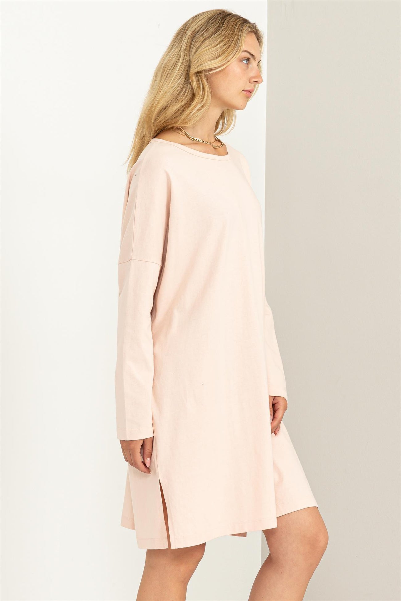 woman wearing a light pink long sleeve dress with side slits and a relaxed fit