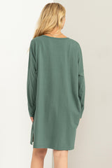 woman wearing a green long sleeve oversized dress with side slits, viewed from the back