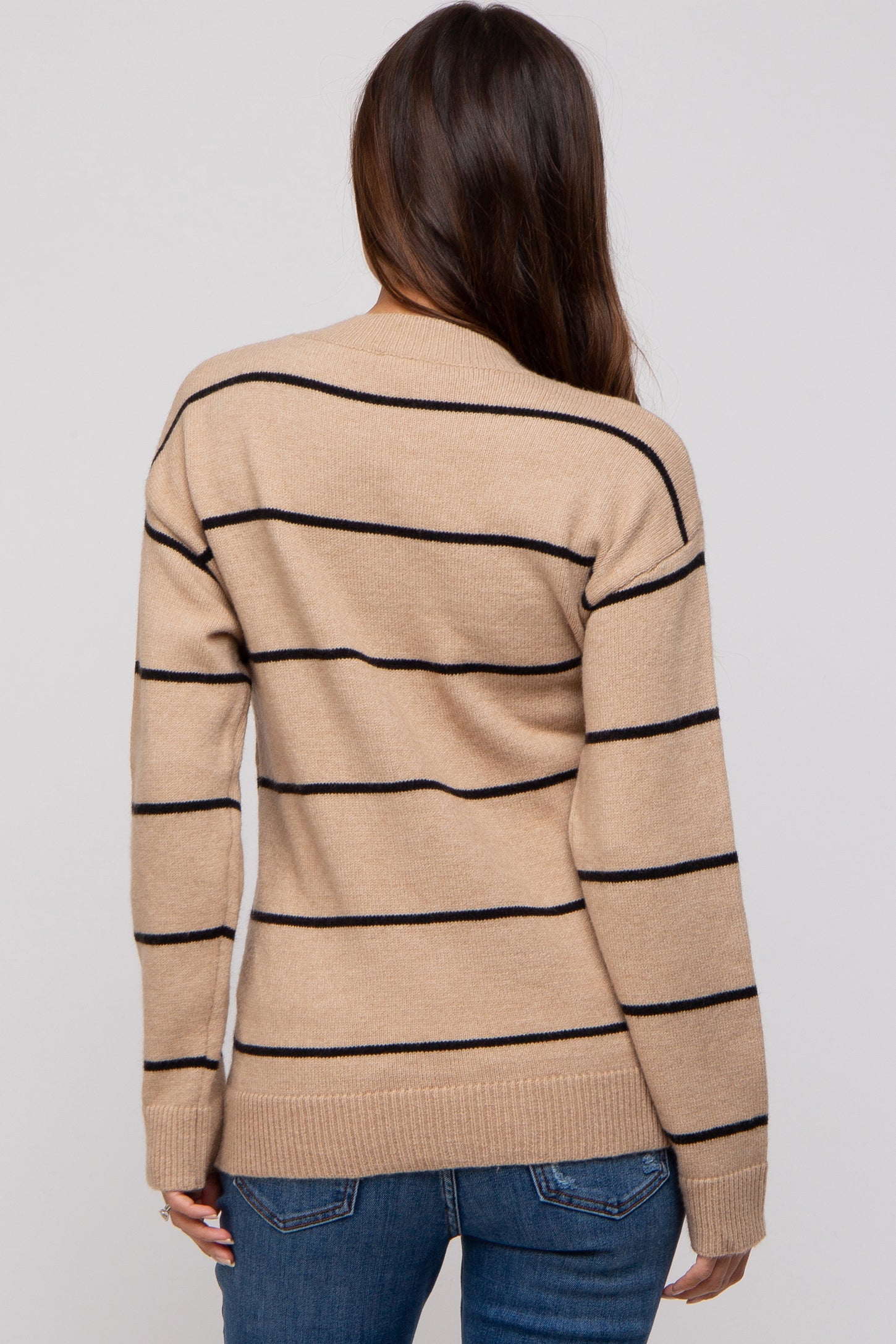 woman wearing a beige striped maternity sweater with black lines, seen from the back