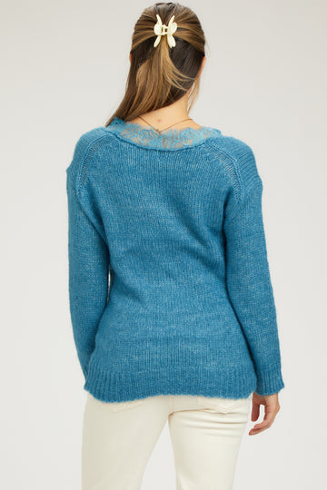 woman wearing a blue maternity sweater with lace detail on the neckline, shown from the back