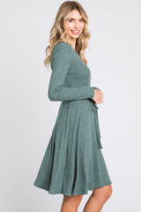 woman wearing a green long sleeve fit and flare dress with a tie waist and flared skirt